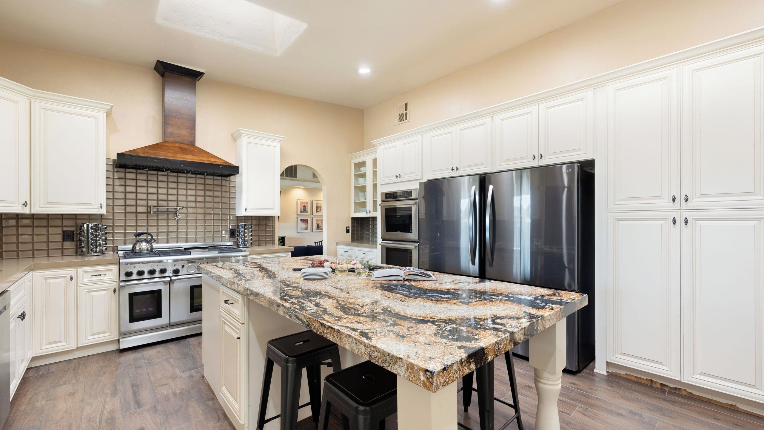 A kitchen with white cabinetry, a granite countertop, stainless steel appliances, and a wood-burning stove.