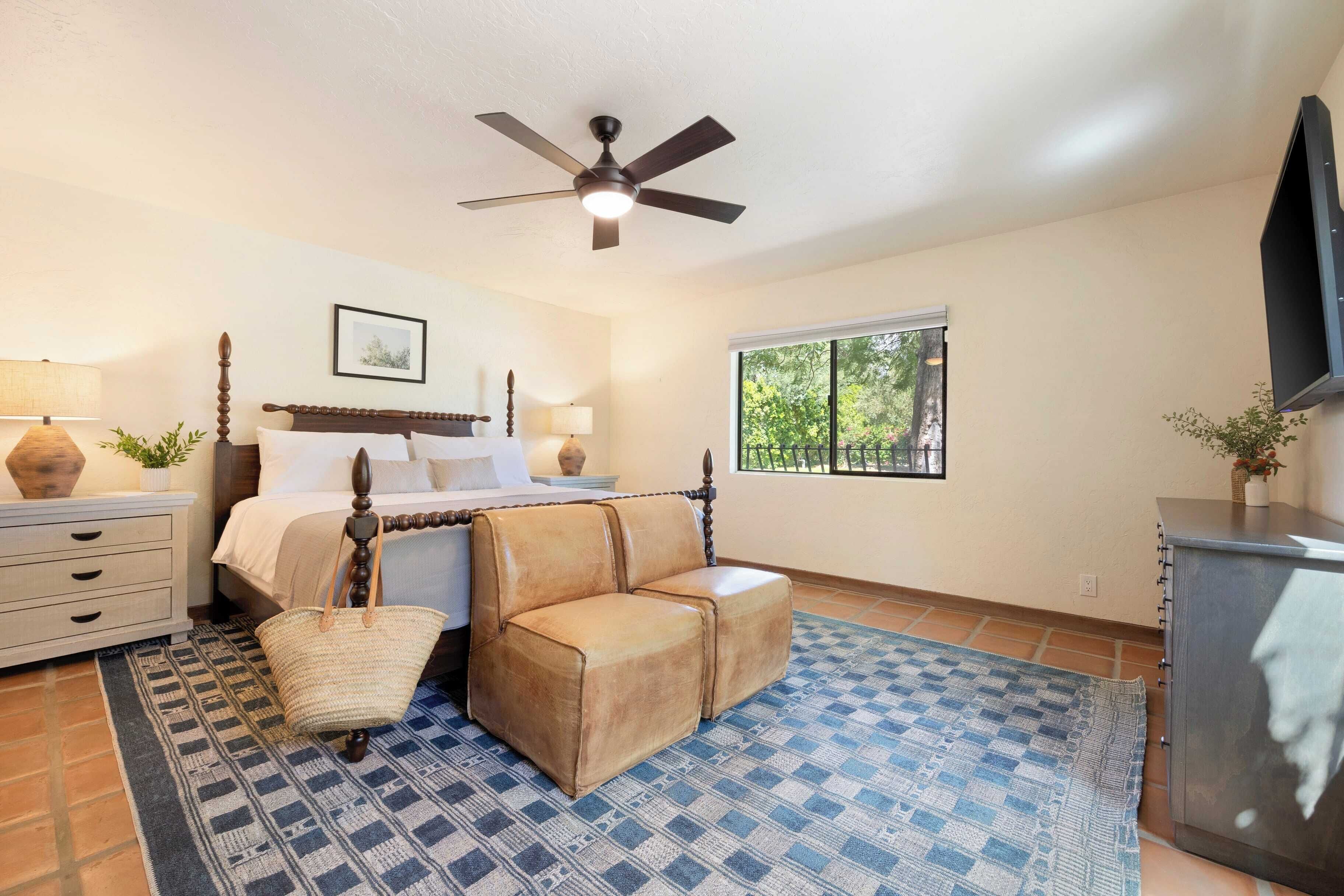 A bedroom with a bed, a ceiling fan, a window, a dresser, and a rug.