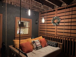 A cozy room with a wooden bed, a window with a view, and a wall-mounted wreath. - Stunning Views, King Bed, outdoor swing bed, Hot Tub, 5 minutes to the GSMNP! (Sevierville)