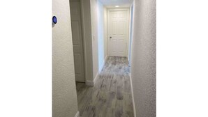 Ein schmaler Flur mit strukturierter Wand und einer Tür am Ende.