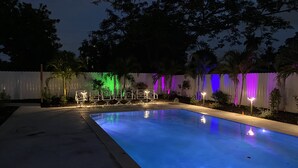 Ein Swimmingpool mit weißem Zaun und Palmen im Hintergrund.