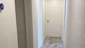 A narrow hallway with a textured wall and a door at the end.