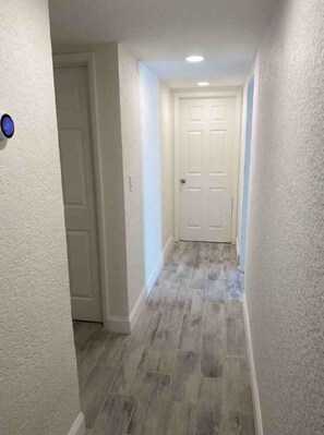 Un couloir étroit avec un mur à texture et une porte au fond.