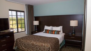 A hotel room with a large bed, two bedside tables with lamps, a dresser, and a television on a stand. - Mountain View Studio + Pool Access (Colorado Springs)