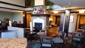 A hotel lobby with a fireplace, seating area, and a television screen displaying a show. - Mountain View Studio + Pool Access (Colorado Springs)