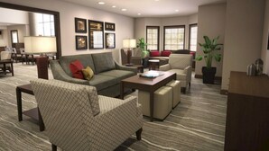En moderne hotellobby med et siddeområde med sofaer og lænestole, et sofabord og en potteplante.