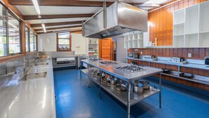 A modern kitchen with stainless steel appliances, a large island, and wooden paneling. - Te Anau Central Backpackers (Te Anau)