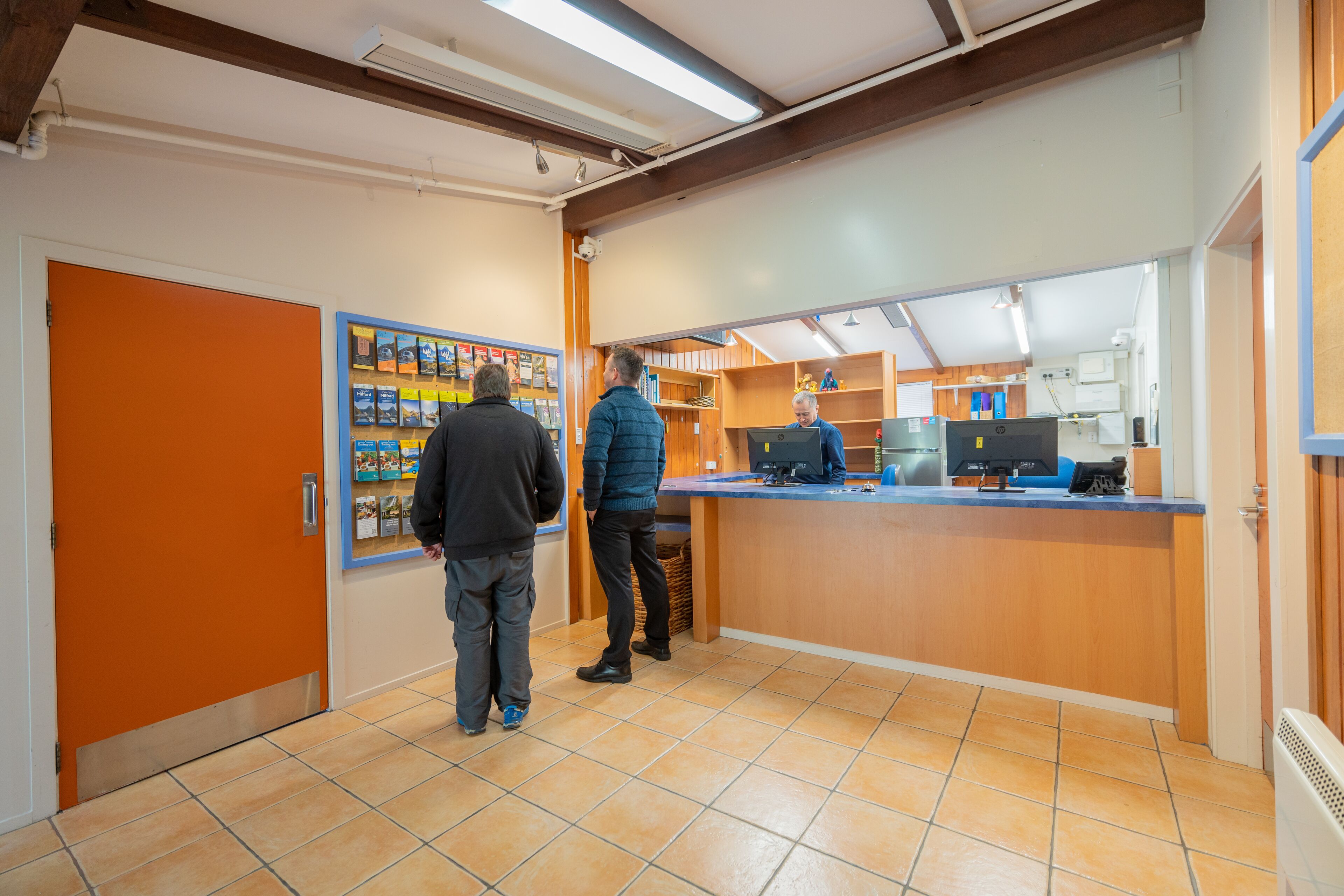 A reception area with a counter, a bulletin board, and a tiled floor.