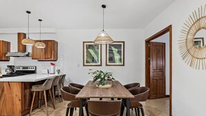 Une cuisine moderne avec un îlot central en bois, des tabourets de bar et des luminaires suspendus.