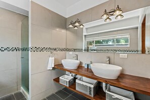 Un baño moderno con dos lavamanos, una ducha y un espejo grande.