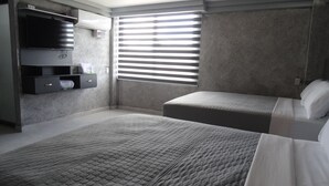 Un dormitorio con dos camas, televisión integrada y ventana con persianas.