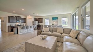 A spacious living room with a large beige sectional sofa, a coffee table, and a kitchen area in the background. - Private Pool & Resort Perks: Home in Davenport (Davenport)