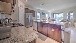 A modern kitchen with granite countertops, stainless steel appliances, and wooden cabinets. - Private Pool & Resort Perks: Home in Davenport (Davenport)