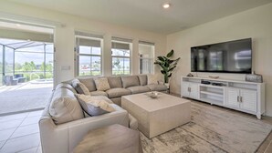 A spacious living room with a sectional sofa, a coffee table, and a TV on a white entertainment unit. - Private Pool & Resort Perks: Home in Davenport (Davenport)