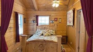 A wooden cabin bedroom with a bed, a ceiling fan, and a window. - A Peace of Heaven LOG Cabins & RV- Cabin #3 (Vanderpool)