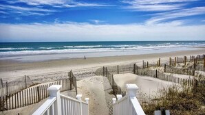 Une vue sur la plage, avec une clôture en bois et une balustrade blanche.