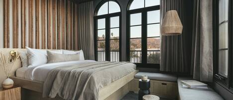 A bedroom with a large bed, a window seat, and a view of the outdoors.