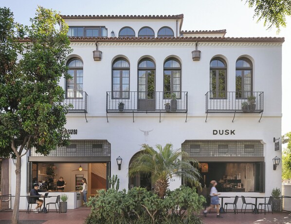 A building with a white facade, multiple balconies, and storefronts labeled 'DUSK'. - Drift Santa Barbara, a Member of Design Hotels (Santa Barbara)