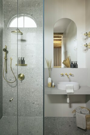 A modern bathroom with a glass-enclosed shower, a white sink, and a mirror with gold accents. - Drift Santa Barbara, a Member of Design Hotels (Santa Barbara)