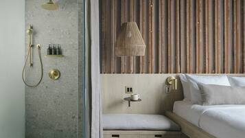 A modern bathroom with a shower, a towel rack, and a shelf with toiletries.