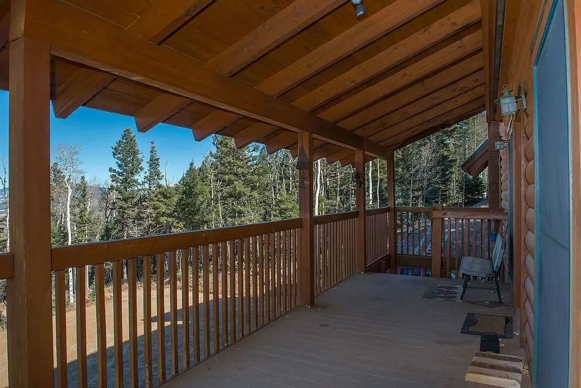 Une terrasse en bois dotée d’une rambarde, qui offre une vue sur une zone boisée.