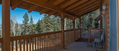 Une terrasse en bois dotée d’une rambarde, qui offre une vue sur une zone boisée.