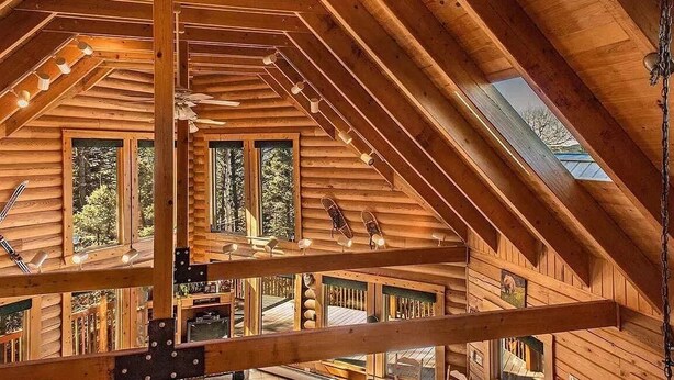 Une cabane en bois avec un toit en pente, de nombreuses fenêtres et un puits de lumière.