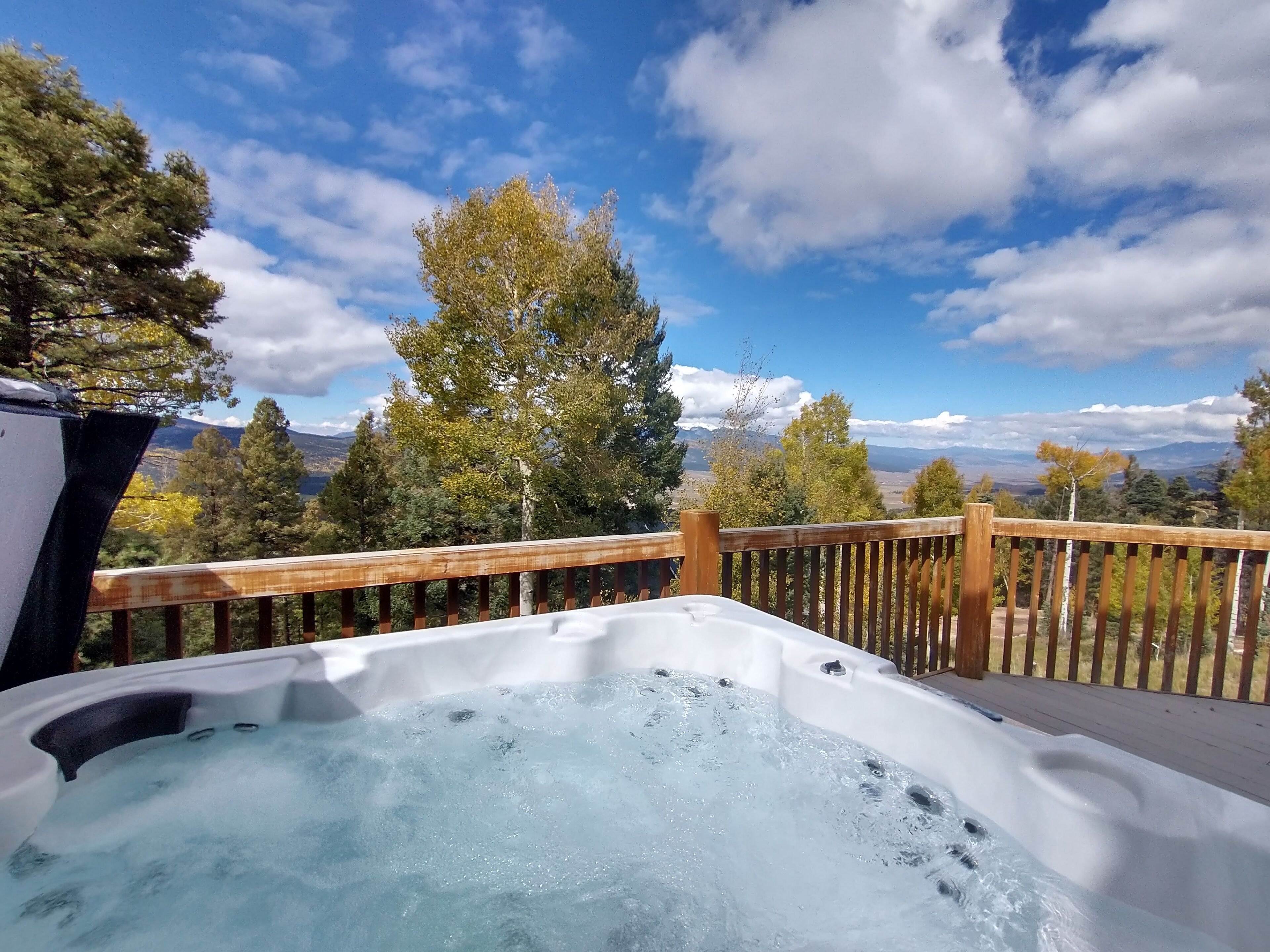 Ett bubbelbad på ett trädäck med en vacker utsikt över bergen.
