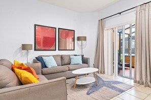 A modern living room with a sofa, a coffee table, and two wall-mounted lamps.