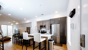 A modern kitchen with stainless steel appliances, a dining area with white chairs, and a wooden floor. - Fantastic 4BR Townhouse W/ HOTTUB (Philadelphia)