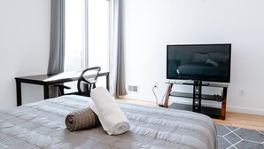 A hotel room with a bed, a desk, a television, and a window with curtains. - Fantastic 4BR Townhouse W/ HOTTUB (Philadelphia)