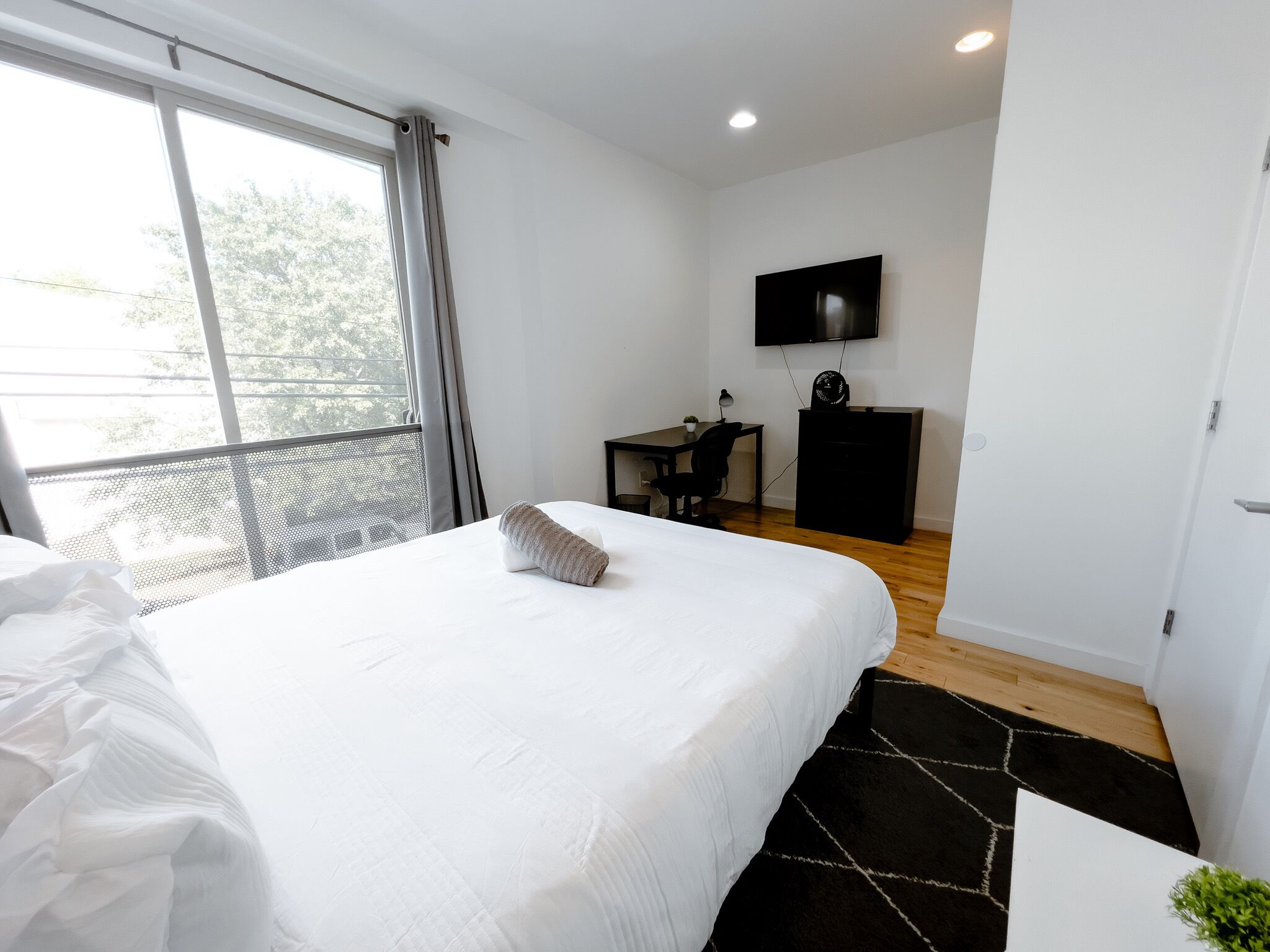 Een hotelkamer met een groot bed, een bureau, een televisie en een balkon met uitzicht.