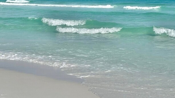Una playa con agua turquesa cristalina y olas suaves.