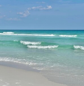 A beach with clear turquoise water and gentle waves.