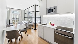 A modern kitchen with a microwave, sink, and oven. There is a dining area with a table and chairs. - GuestReady - Modern Apartment in Bolhão (Porto)