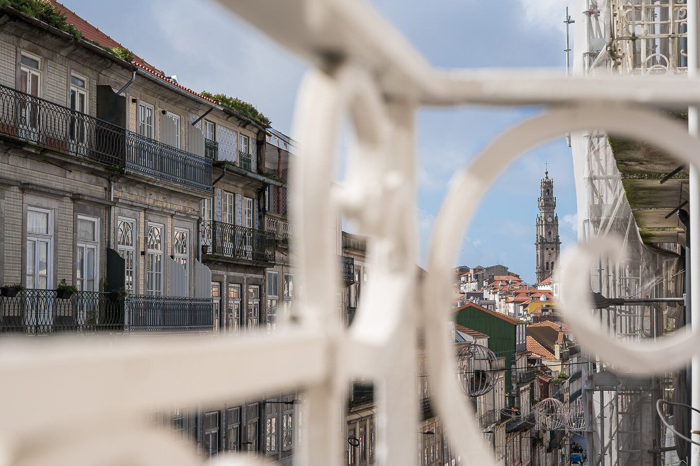 A historic building with ornate balconies and a clock tower in the background.