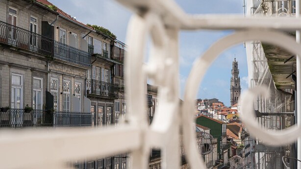 A historic building with ornate balconies and a clock tower in the background.