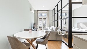 A modern living room with a round dining table, two chairs, a sofa, and a bed. - GuestReady - Modern Apartment in Bolhão (Porto)