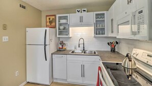 A compact kitchen with white cabinets, a built-in microwave, a stove, and a refrigerator. - Mountain View Home Steps to Amphitheater Park (Mountain View)