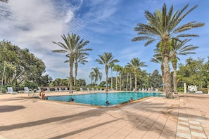 A pool area with palm trees, lounge chairs, and a clear sky. - Relax & Play: Townhome Near Disney & More! (Reunion)