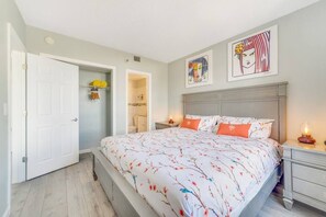 A bedroom with a bed, nightstands, a door, and artwork on the wall. - Fabulous Resort Condo with Heated Pool! (Orange County)