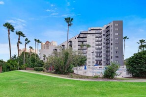 A multi-story hotel with balconies, surrounded by palm trees and a well-maintained lawn. - Fabulous Resort Condo with Heated Pool! (Orange County)
