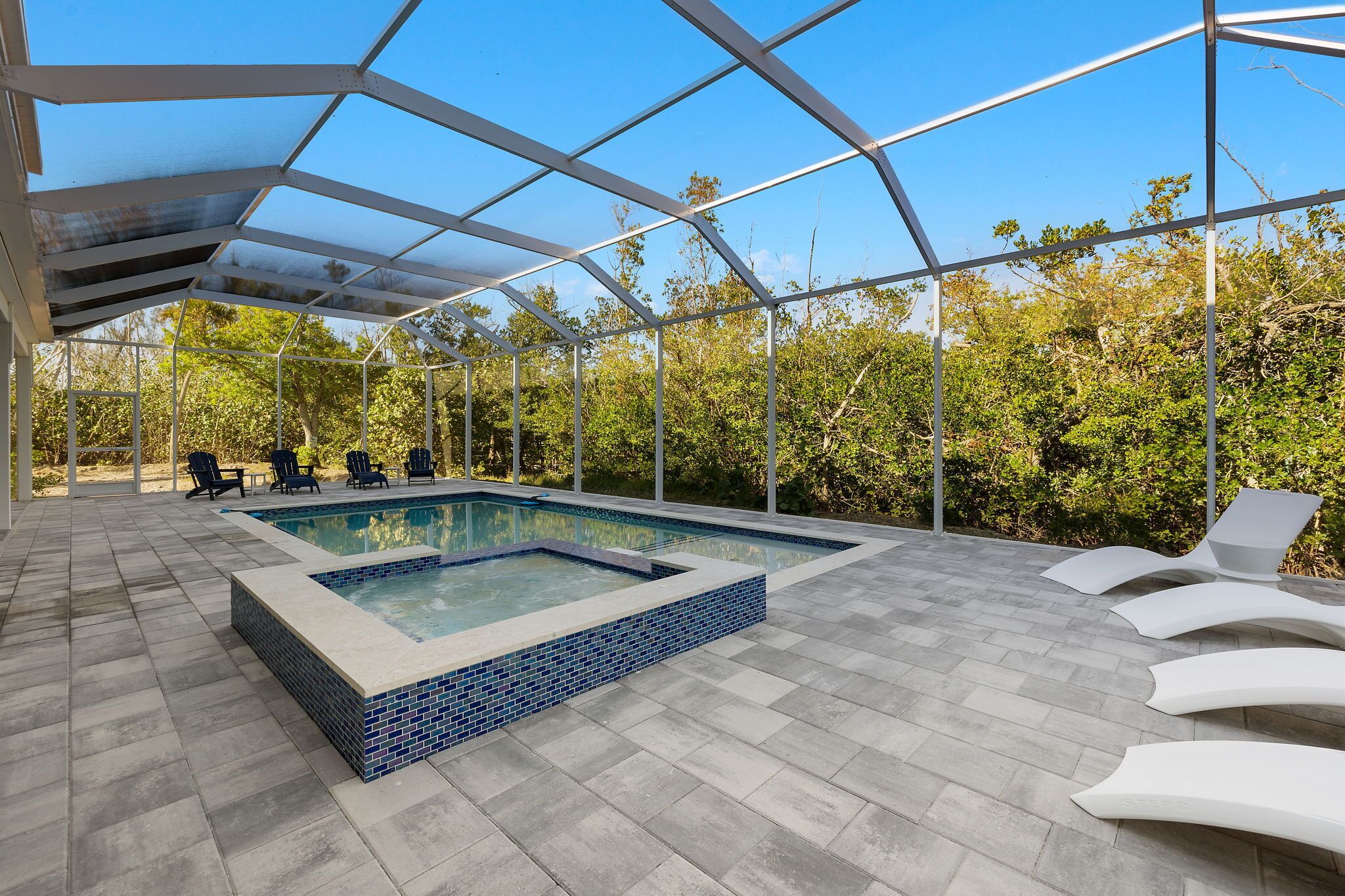 Una piscina exterior cubierta con suelo de baldosas y sillones de descanso.