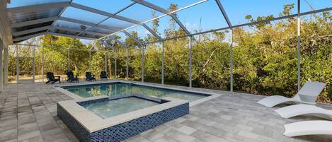 Una piscina exterior cubierta con suelo de baldosas y sillones de descanso.