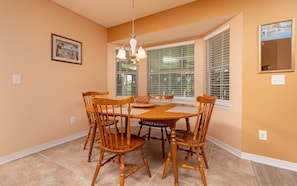 A dining area with a wooden table and chairs, a chandelier, and large windows with blinds. - Luxury Executive Home • Perfect for Groups (Pace)