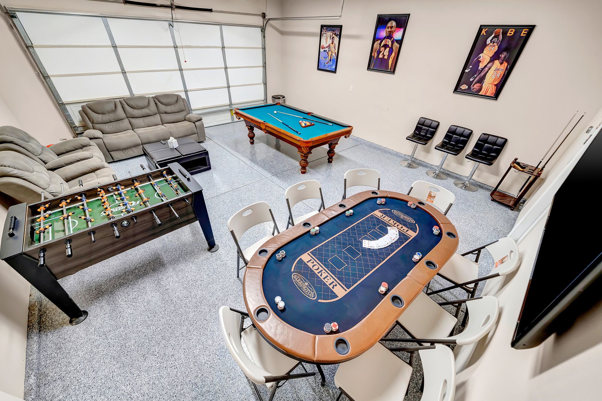 Une pièce équipée d’un baby-foot, d’une table de billard et d’une table de poker. Quatre chaises sont disposées autour de la table de poker.