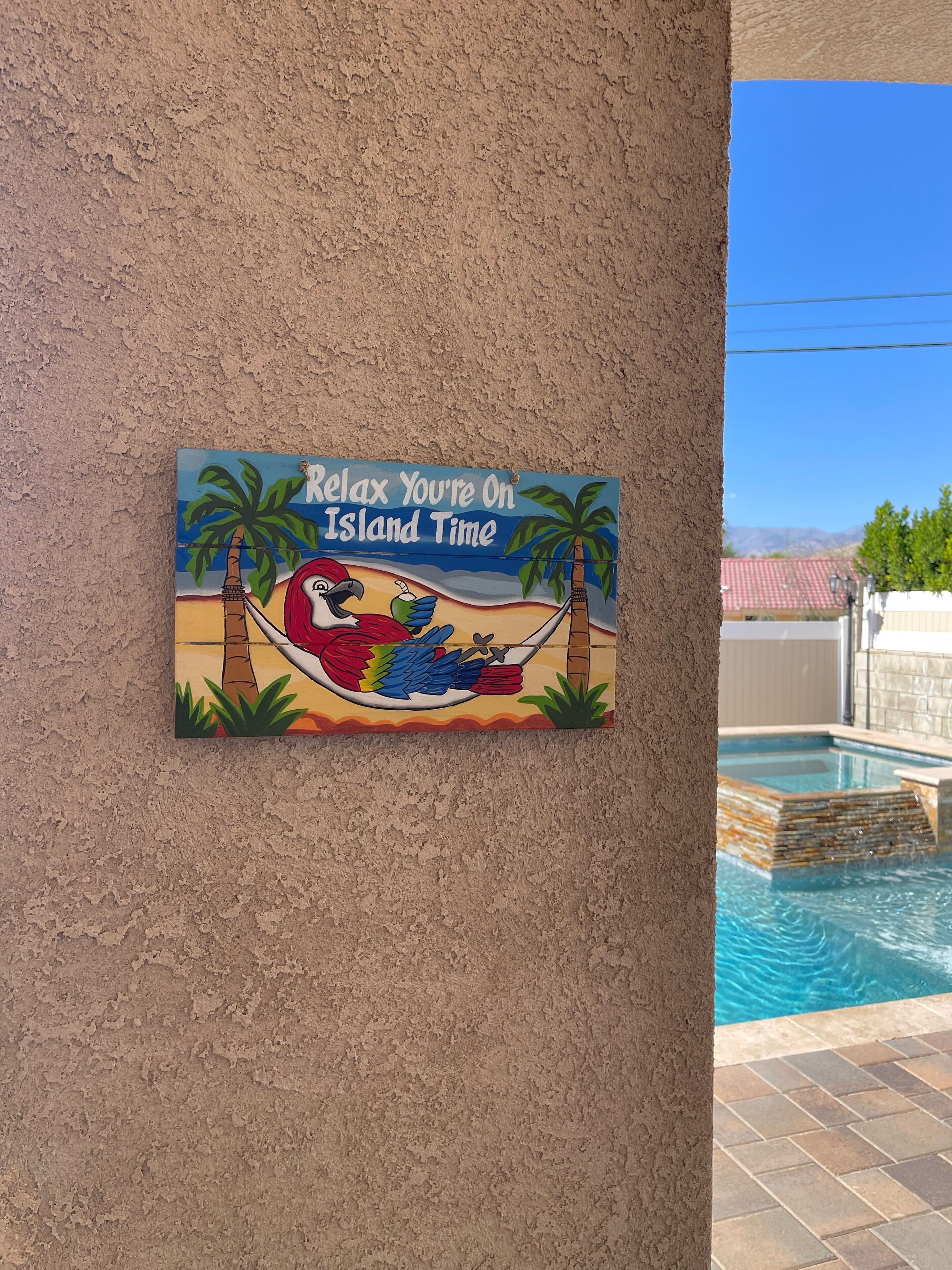 Un letrero en la pared con una escena de playa y el texto 'Relax You're On Island Time'.