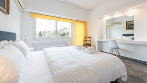 Una habitación de hotel con cama, escritorio, silla, ventana con cortinas y espejo.