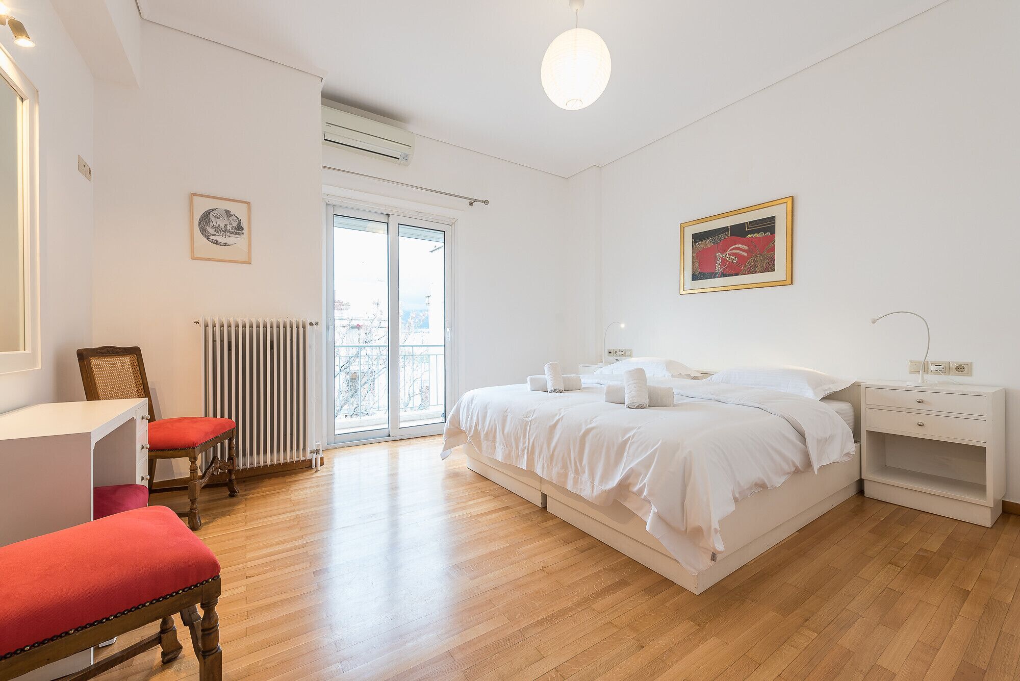 Une chambre à coucher avec un lit, des tables de chevet, une chaise, un radiateur et une fenêtre.