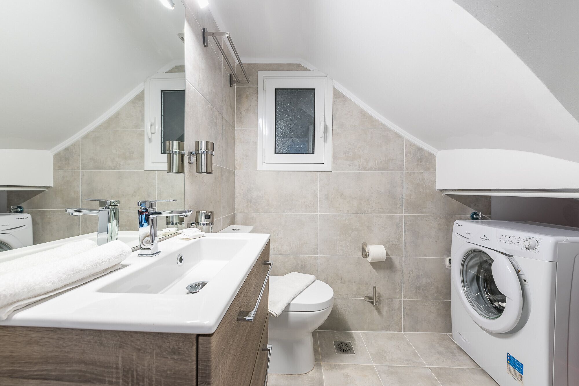 Une salle de bain moderne dotée d’un double lavabo, de toilettes et d’un lave-linge encastré.